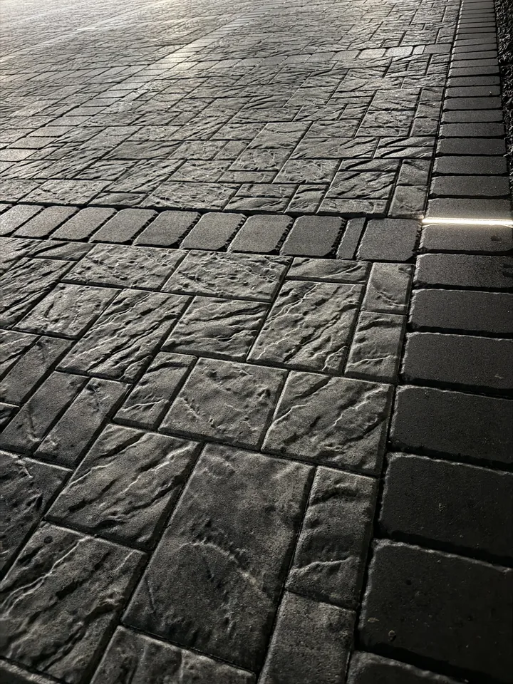 Close view of charcoal slate-textured pavers with a soldier-course border, joints sanded and aligned