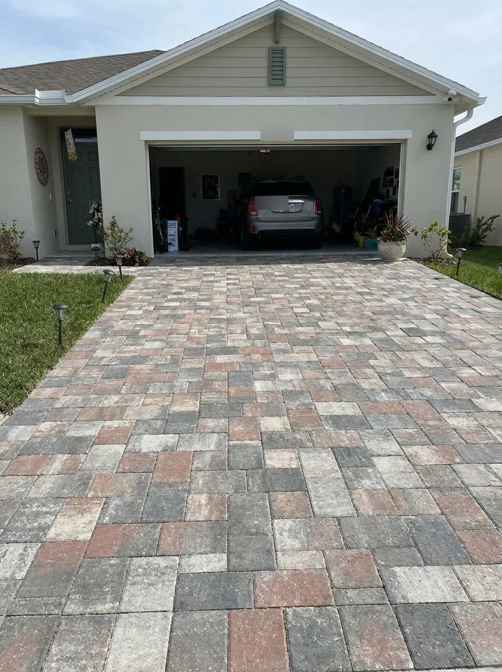 Random-ashlar paver driveway in mixed gray, tan and terracotta tones in front of a two-car garage